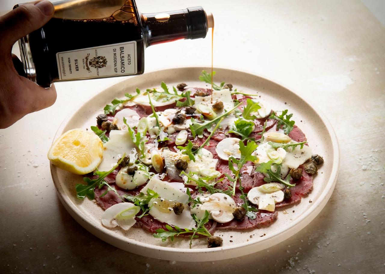 Beef carpaccio being finished with balsamic
